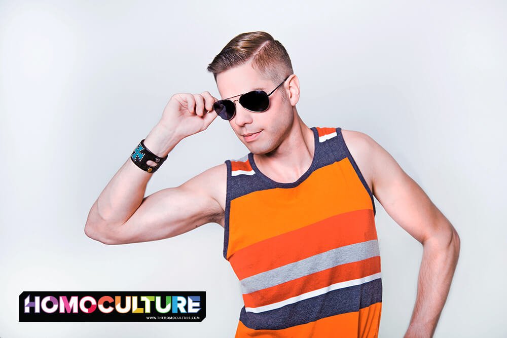 A cute, muscular young gay man wearing a tanktop and sunglasses.