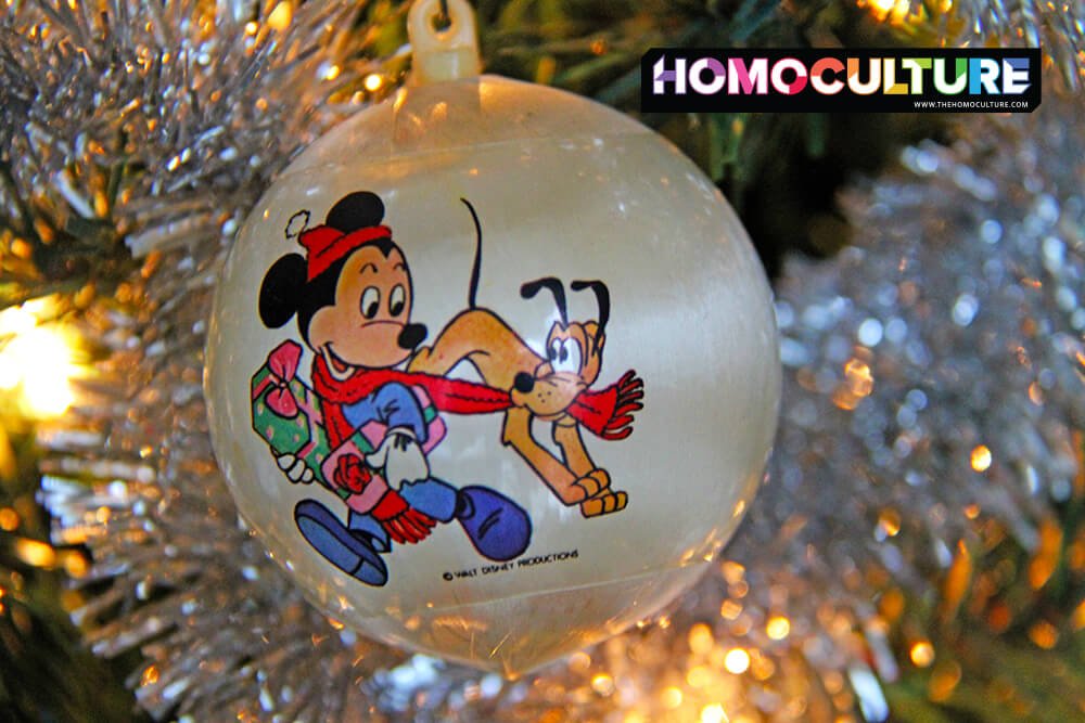 A Disney oranament hanging on a Christmas tree.
