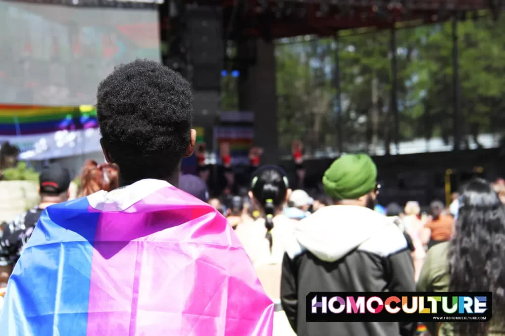 A guy wearing a bisexual Pride flag at the 2022 Winnipeg Pride festival.