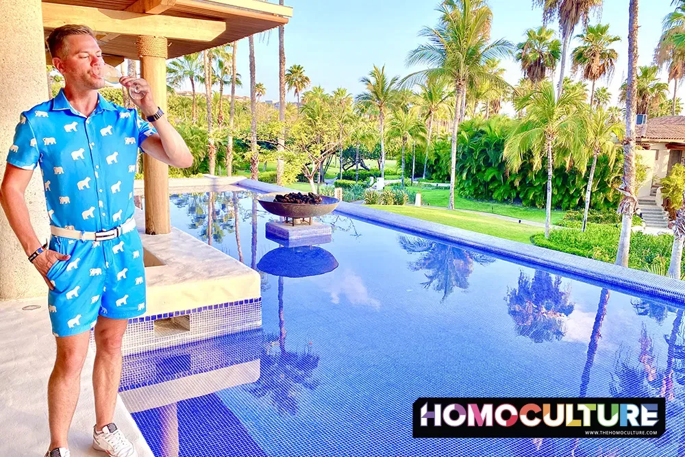 Man in a blue onesie drinks a glass of Champagne overlooking the St Regis Resort in Nayarit, Mexico. 