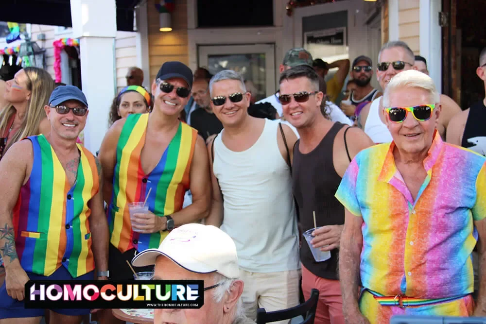 A group of friends wearing Pride outfits watching the 2023 Key West Pride Parade.