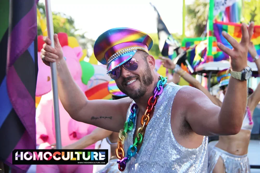 A man decked out in Pride accessories and a sequin shirt, marching in the 2023 Key West Pride Parade.