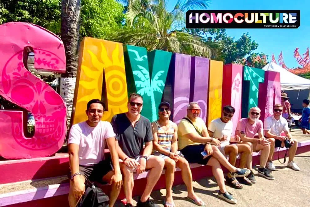 A group of gay men in front of a Sayulita sign.