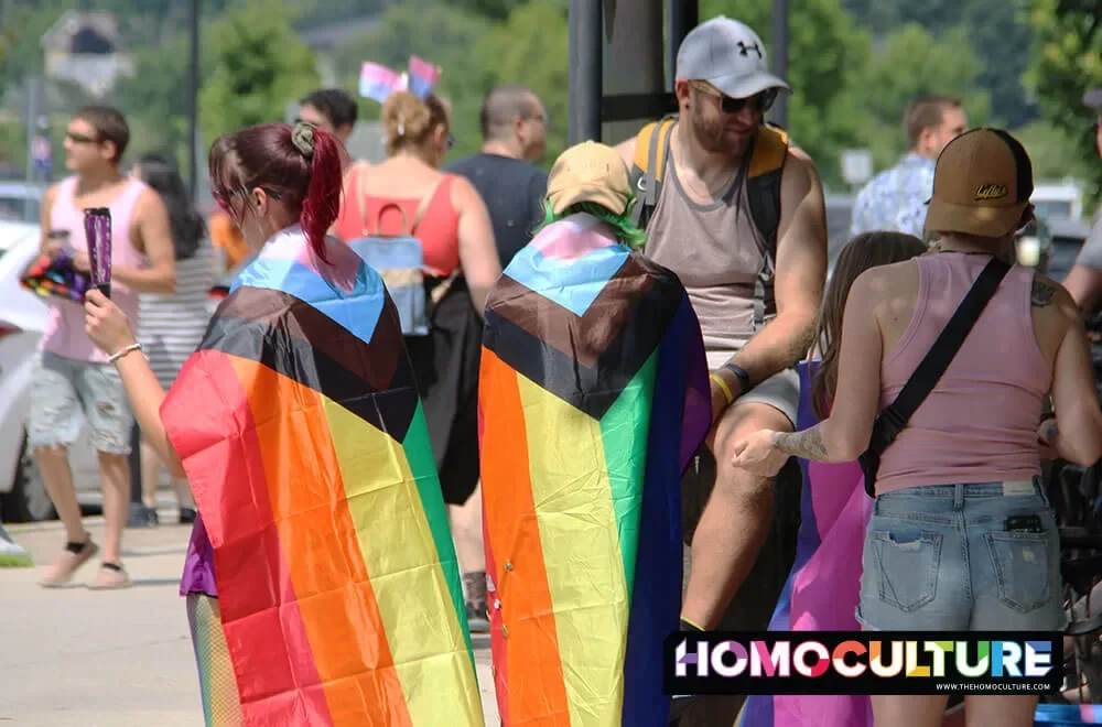 People draped in Progressive Pride flags at the 2023 Fredericton Pride parade. 