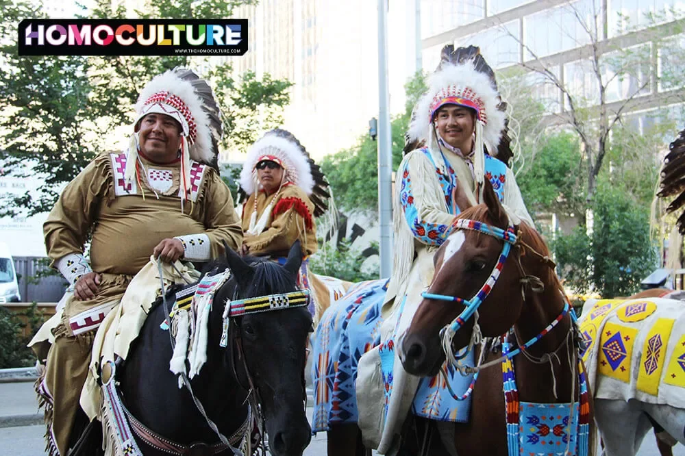 First Nations people, in traditional clothing, riding horses in downtown Calgary during the 2023 Calgary Stampede. 