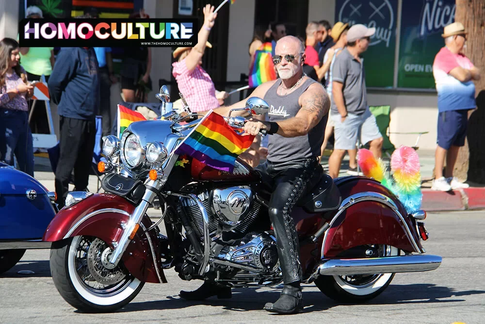 A an on a vintage motorcycle with a Pride flag during the 2022 Palm Springs Pride parade. 