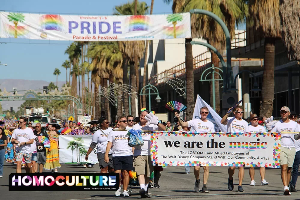 A large group holding a banner makes their way down the 2022 Palm Springs Pride Parade.