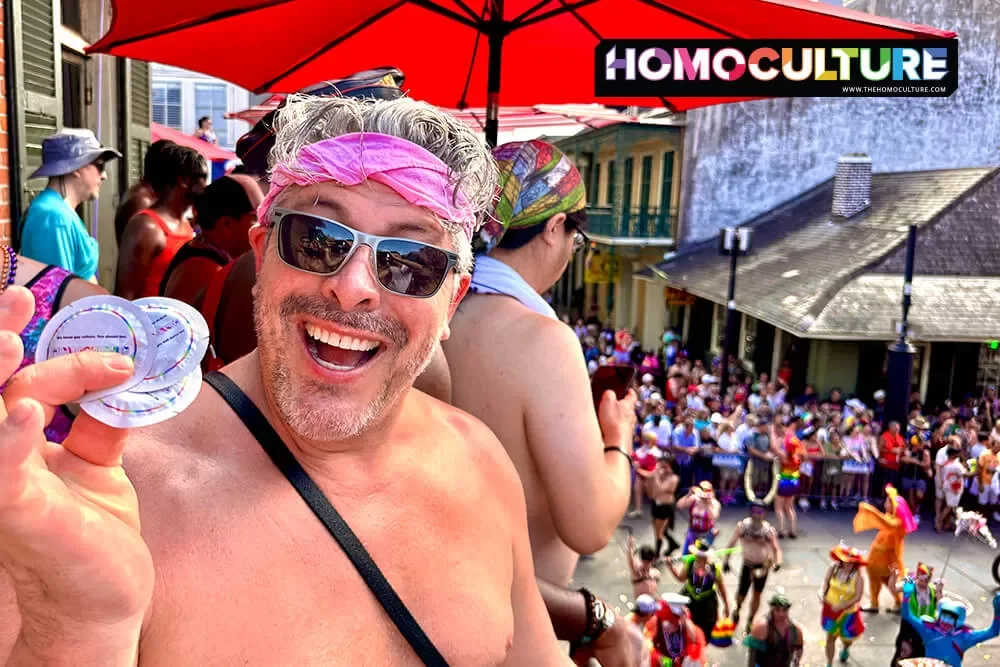 A shirtless man holding a handful of ONE Condoms at Southern Decadence 2023. 