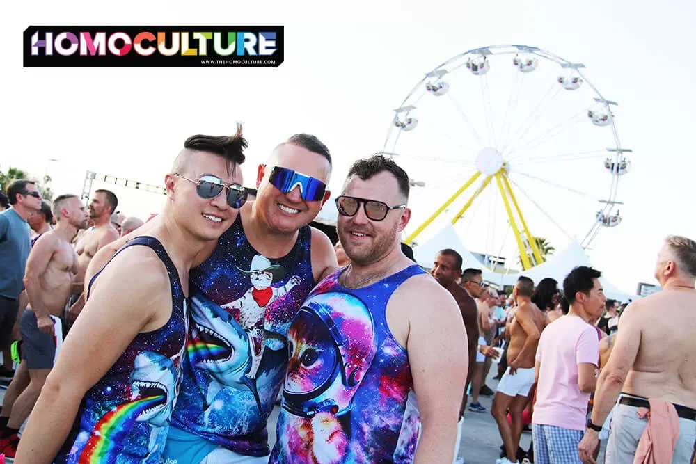 A group of friends with a ferris wheel in the background at the Sunday Orbit T-Dance during White Party Palm Springs 2023. 