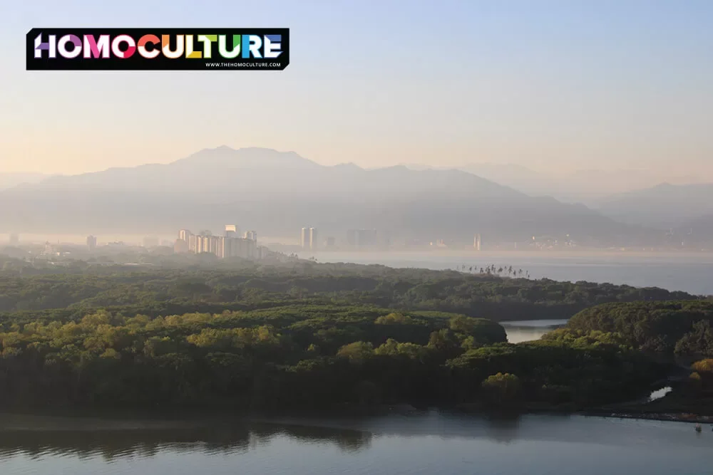 A scenic sunrise from Vidanta Resort, looking over the jungle toward Puerto Vallarta; mist hands over the city and mountains in the background.
