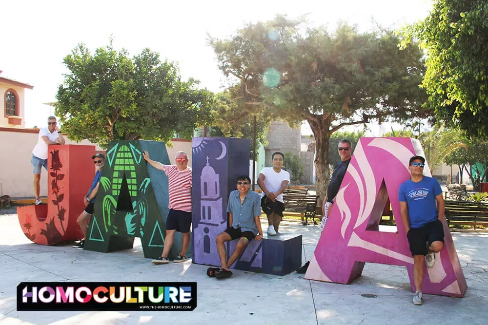 A group of gay men posing at a landmark sign in Jala, Mexico.