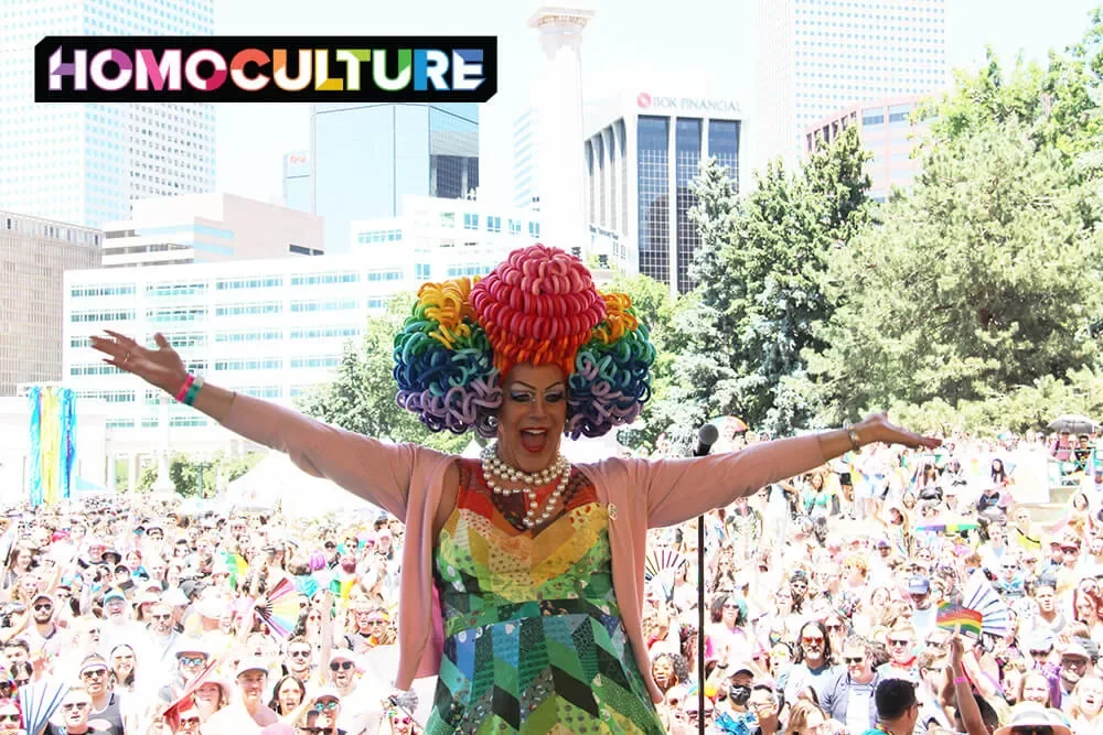 A drag queen wearing a rainbow wig and dress on stage at Denver PrideFest 2023.