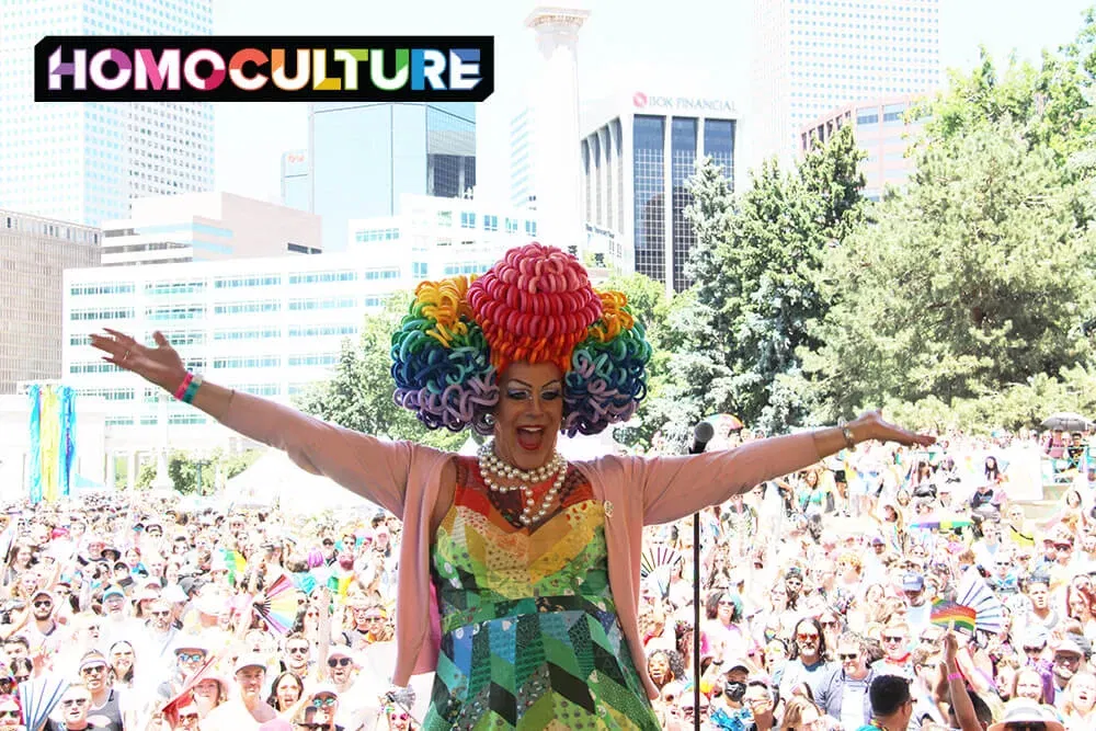 A drag queen wearing a rainbow wig and dress on stage at Denver PrideFest 2023. 