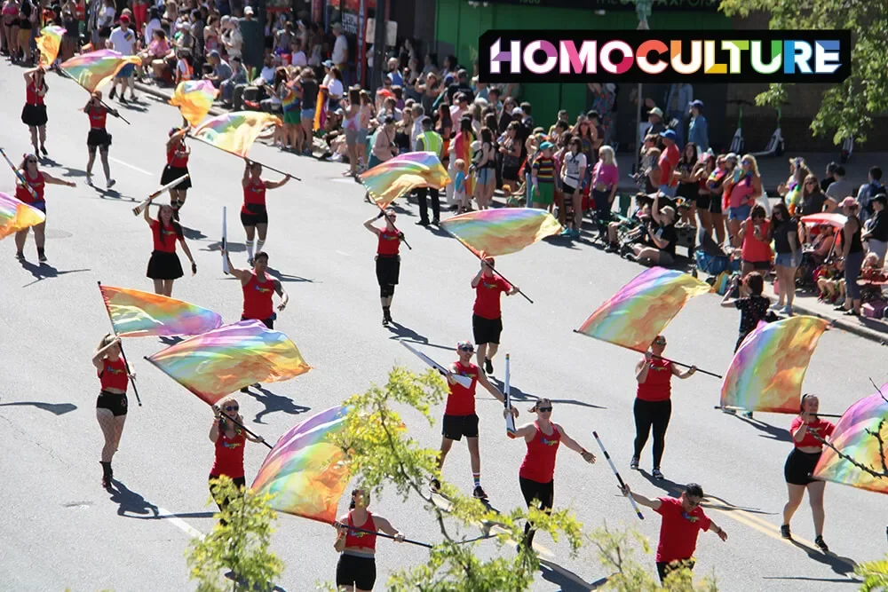 A group of marchers carrying colorful flags march in the 2023 Denver Pride Parade. 