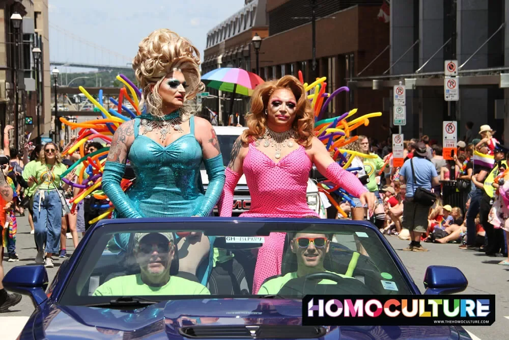 Two drag queens sitting in the back of a convertible during the 2022 Halifax Pride parade.