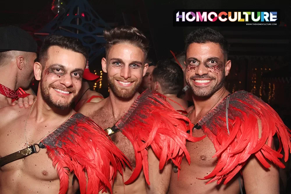 A group of friends at a gay club wearing matching, homemade outfits made of red feathers. 