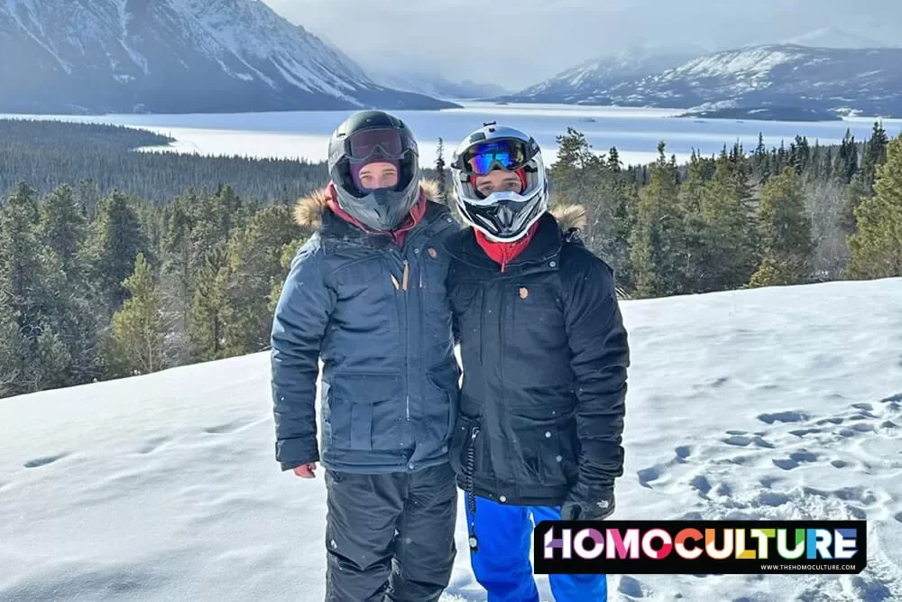 A gay couple posing for a photo with the Yukon wilderness in the background. 