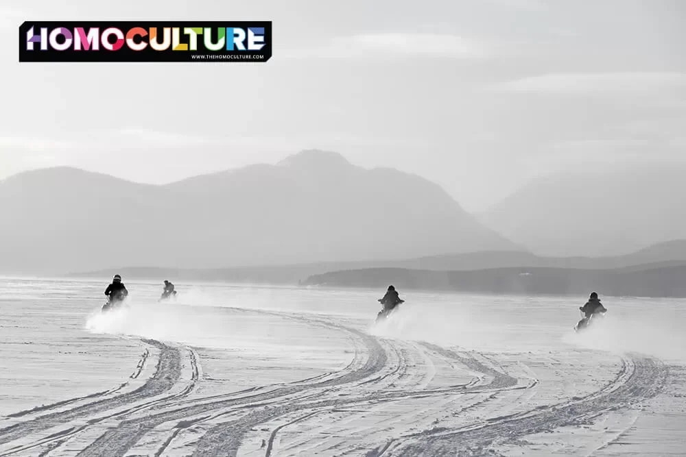 A group of friends snowmobiling on a frozen lake in the Yukon Territory. 