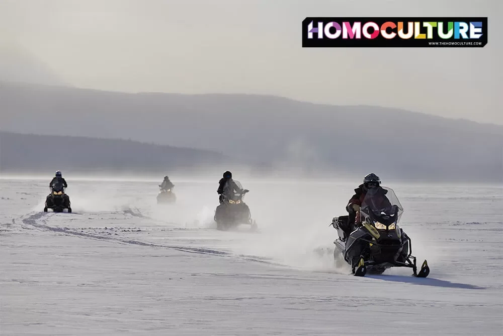 A group of friends riding on a guided snowmobile tour on Tagish Lake at Southern Lakes Resort. 