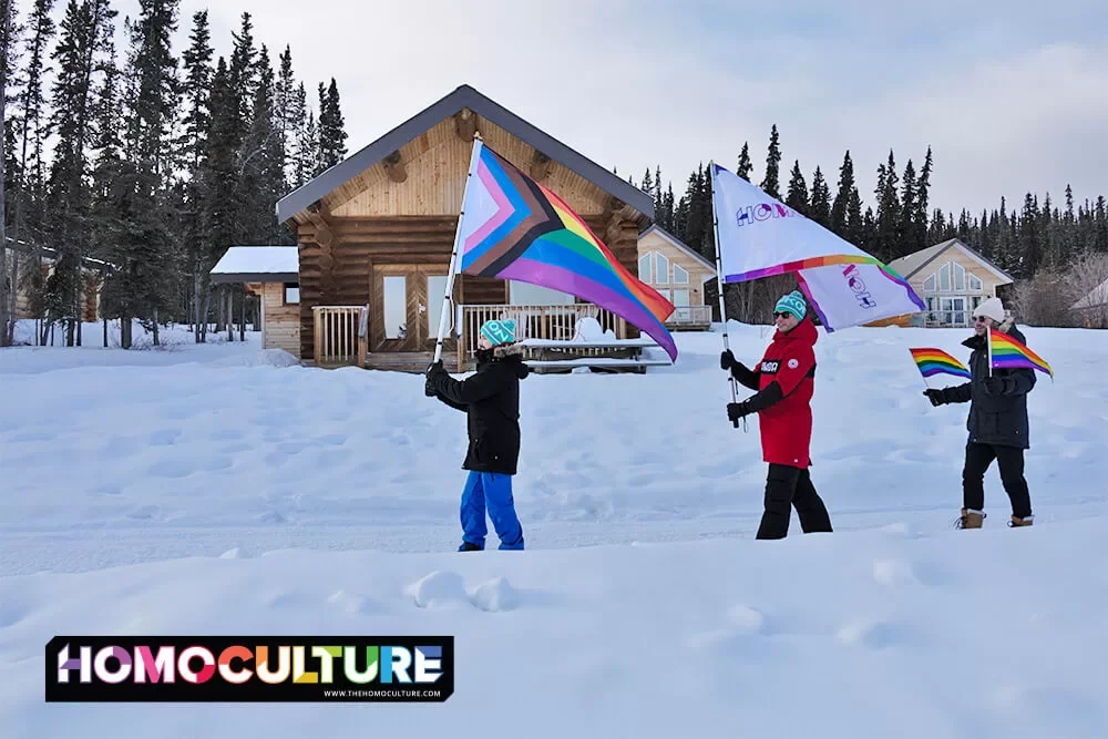 A group of LGBTQ+ friends marching with Pride flags on a winter day in the Yukon. 