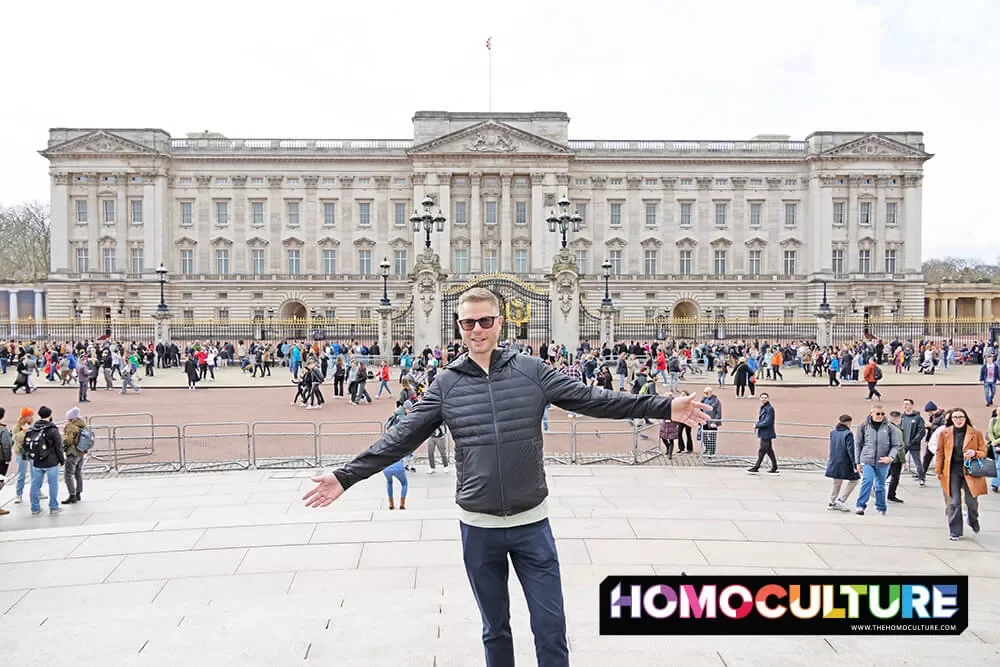A gay man posing in front of Buckingham Palace in London, United Kingdom.