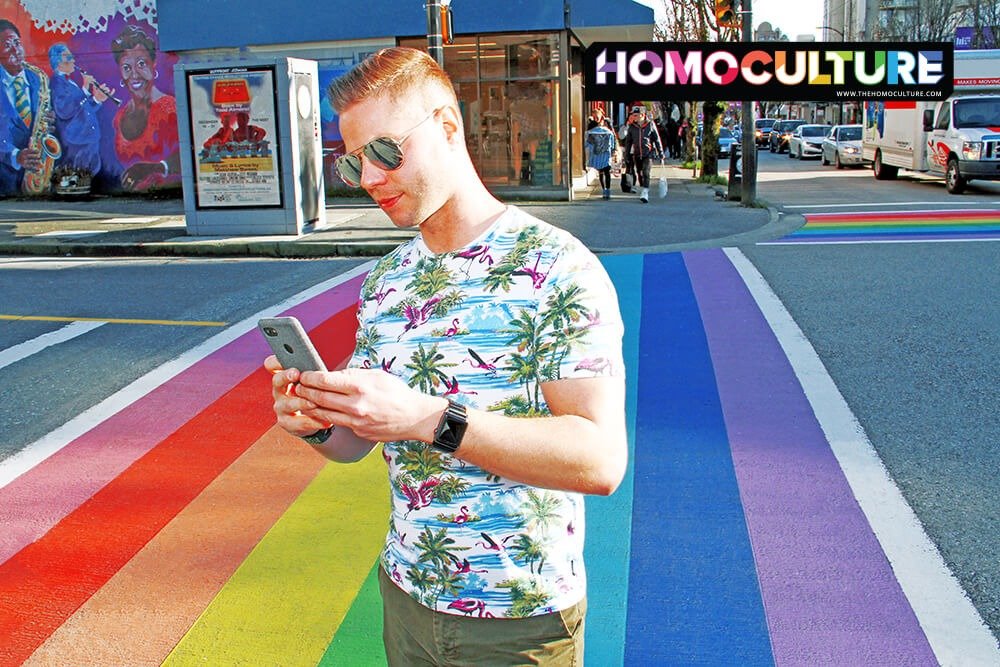 A gay man on his iPhone at a Pride crosswalk.