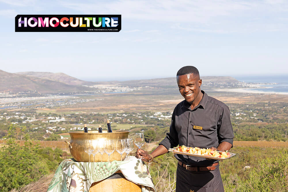 Cape Point Vineyards staff member serving wine and snacks at a private hilltop tasting with panoramic ocean and valley views, arranged through Jeep Tours Cape Town.
