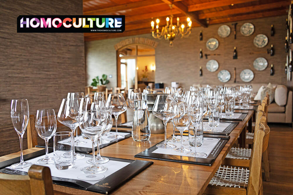 Elegant wine tasting room at DeGrendel Wine Estate near Cape Town, South Africa, with rows of glasses set for a curated tasting experience under a chandelier-lit wooden ceiling.