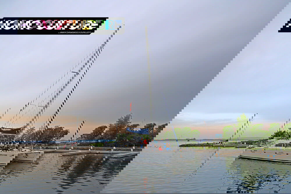 Catamaran with passengers sailing out of the Thunder Bay marina at sunset, with calm waters, a pastel sky, and the Sleeping Giant visible in the background.